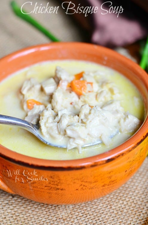  Chicken Bisque Soup in an orange bowl with a spoon scooping some out 