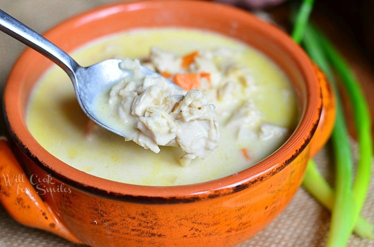  horizonal photo of Chicken Bisque Soup in an orange bowl with a spoon scooping some out 