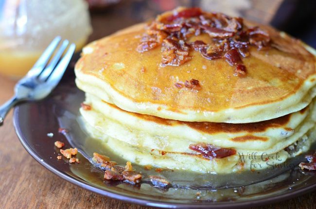 stack of Maple Bacon Pancakes on a plate with a fork on a wood table 