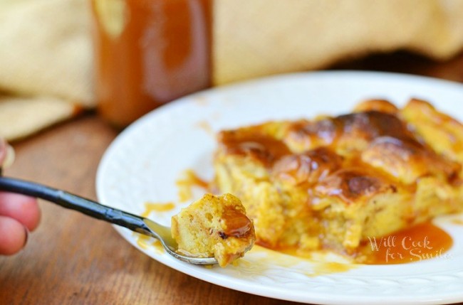 Pumpkin Bread Pudding with Caramel over it on a white plate with a spoon of it 