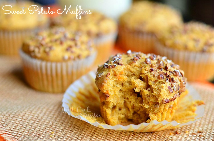 close up view of sweet potato muffins on burlap table cloth with jug of milk in background all on orange colored wood table