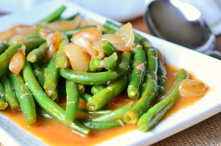 French Green Beans with onions on top on a white plate 