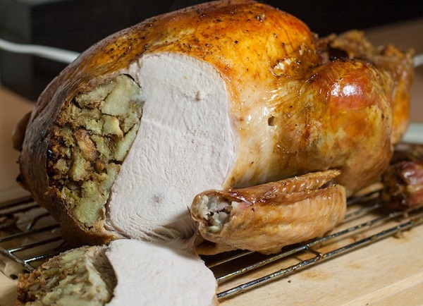 turkey with stuffing with a slice taken off laying on the cutting board 