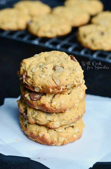 Cookies stacked up on wax paper on a black counter top 