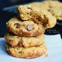 4 peanut butter oatmeal cookies with chocolate chips stacked on wax paper on black table