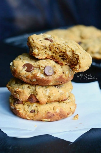 Peanut Butter Oatmeal Cookies with Chocolate Chips stacked up on wax paper with a bite out of the top of them 