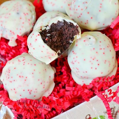 peppermint oreo bites in decorative gift box with shredded red paper with one bite in top