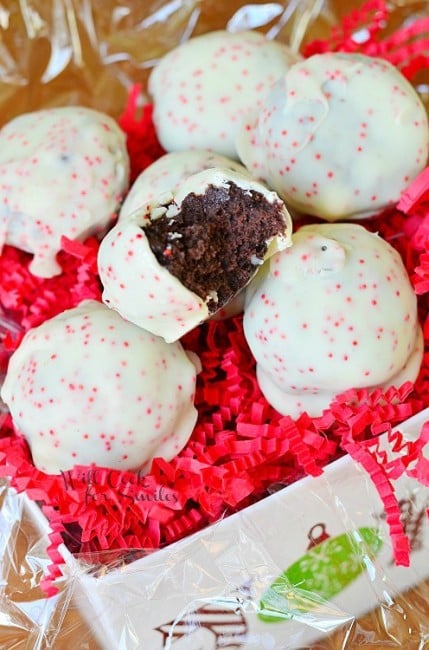 Peppermint Oreo Bites are covered with white chocolate and pink sprinkles with a bite out of one