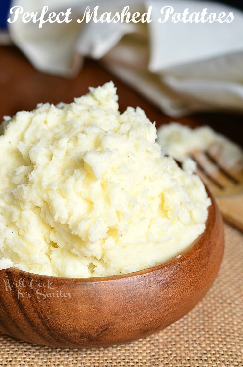 These Perfect Mashed Potatoes are in a wooden bowl on top of a brown place mat 