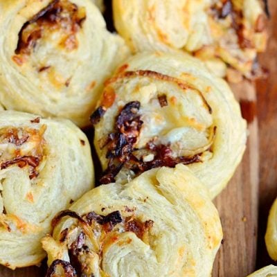 view from above of caramelized onion cheest pinwheels on a brown cutting board