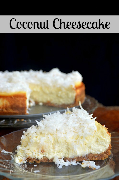 1 slice of coconut cheesecake on clear glass plate in front of rest of cake on glass cake presenter in background