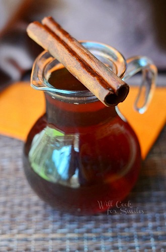 Cinnamon Dolce syrup in a glass serving container with a cinnamon stick across it 
