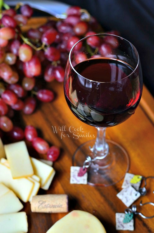  Cheese on a cutting board with red wine in a glass and grapes and cheese on a cutting board 