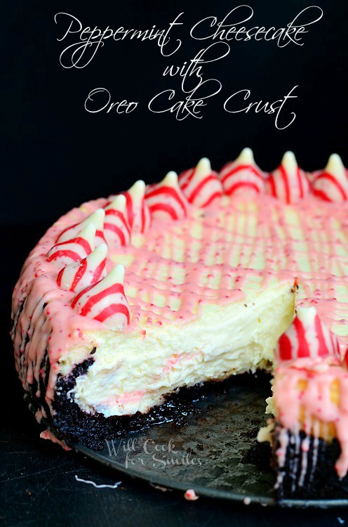 Peppermint Cheesecake with peppermint kisses along the outside and  with Oreo Cake Crust with a slice out of it 