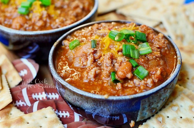 bowl of chili in a blue bowl with green onions sliced on top 