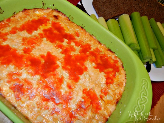 Buffalo Chicken Dip in a green casserole dish 