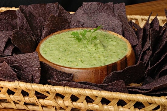 salsa vere in a wood in a basket with purple chips around it 
