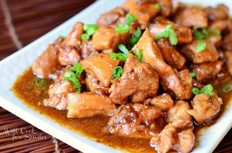 Chicken Teriyaki on a white plate with green onions sliced on top 