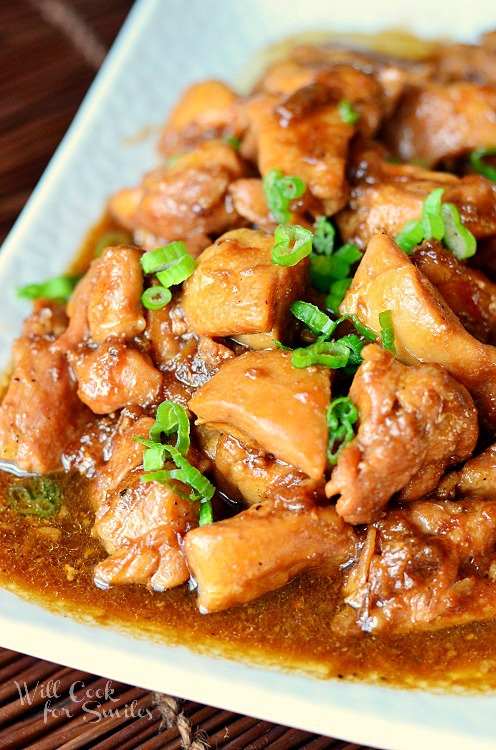 Chicken Teriyaki on a white plate with green onions sliced on top 