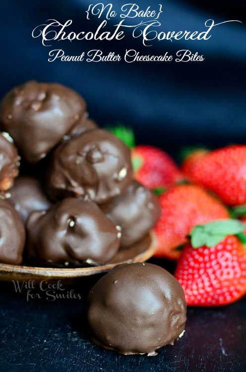 Peanut Butter Cheesecake Bites on a black counter with strawberries to the right 