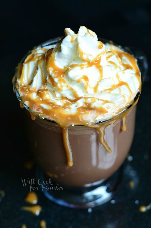 Caramel Hot Chocolate with whip cream and caramel sauce on top and caramel sauce coming over the sides 