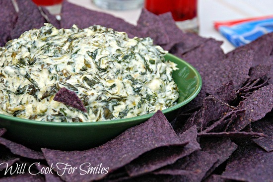 Spinach Parmesan dip in a green bowl with purple tortilla chips 