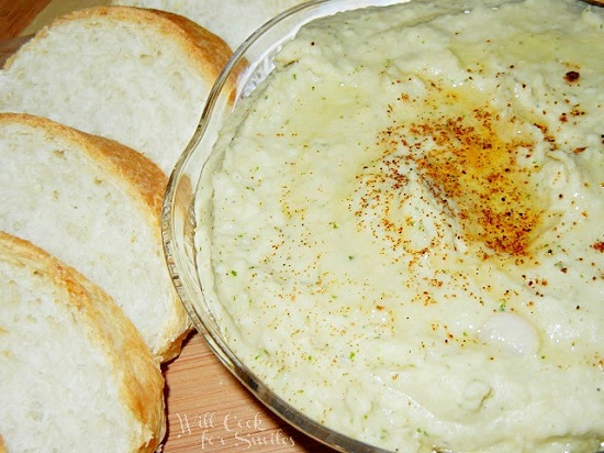White Bean Dip in a glass bowl with bread sliced to the left 