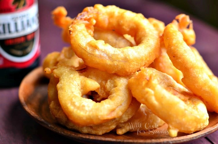 close up view of view from above of fried beer batter onion rings in a wood bowl