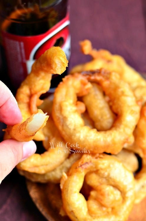 hand holding 1 onion ring with bite in it above view from above 