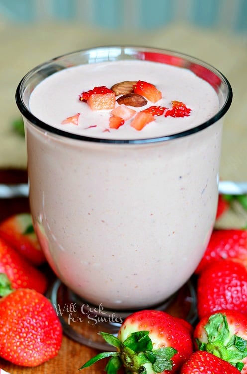 close up of Chocolate Covered Strawberry Protein Shake with sliced strawberries on top and whole strawberries around the outside 
