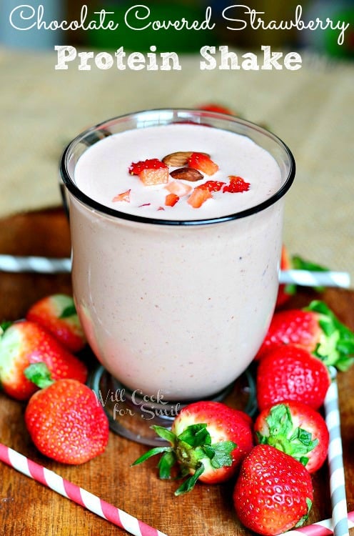 Chocolate Covered Strawberry Protein Shake in a glass with sliced strawberries in the glass and whole strawberries around the outside of the glass 