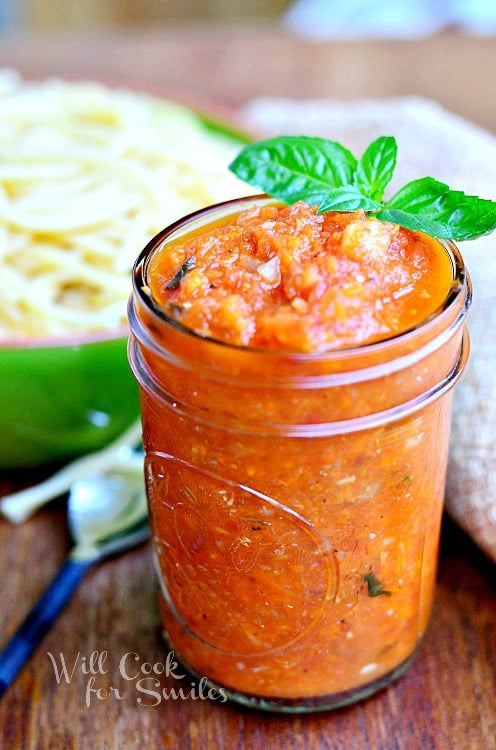 Homemade Marinara sauce in a jar with some basil on the side 