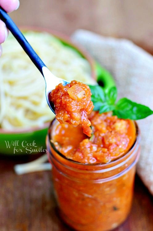 Marinara Sauce in a jar with a spook lifting some out 