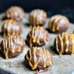 close up view of salted caramel brownie truffles on a stone cutting board each truffle covered in caramel drizzle and salt
