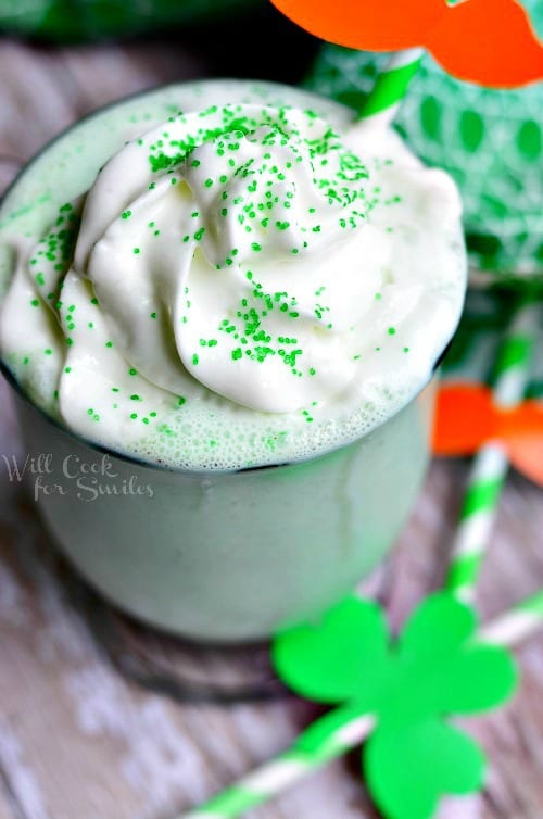 St. Patrick's Day Milkshake in a glass cup with whip cream and green sprinkles on top with a green and white straw
