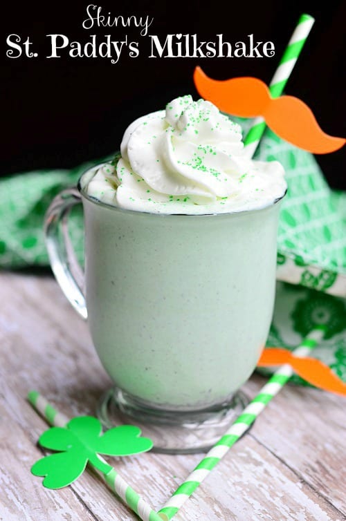 St. Patrick's Day Milkshake in a glass cup with whip cream and green sprinkles on top with a green and white straw