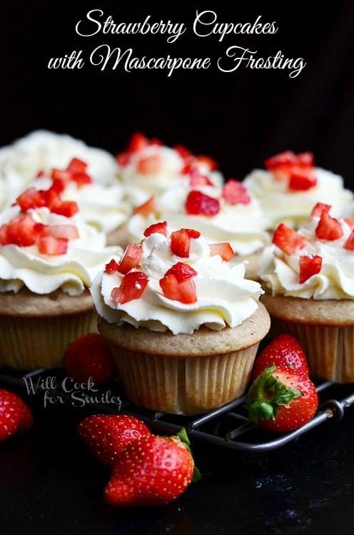 Strawberry Cupcakes with Mascarpone Frosting on a cooling rack with strawberries around it