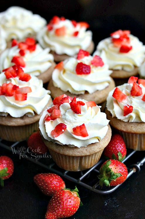 Strawberry Cupcakes with Mascarpone Frosting on a cooling rack with strawberries 