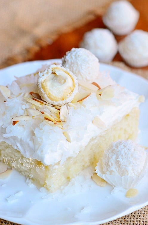 Raffaello Poke Cake Coconut Cake with White ChocolateCoconut Cream and Whipped Topping on a white plate 