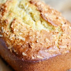 whole loaf of coconut key lime bread on a wood plate on a wooden table with white table cloth