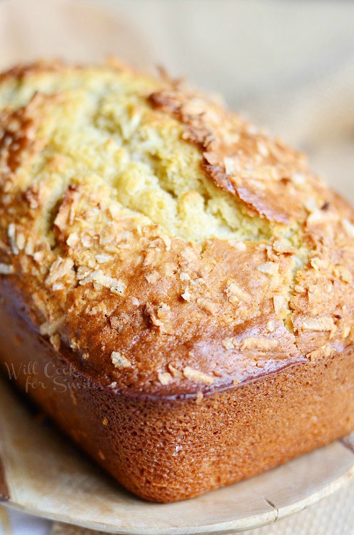 whole loaf of coconut key lime bread on a wood plate on a wooden table with white table cloth