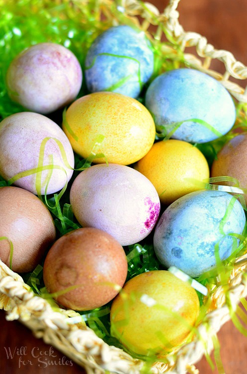 colored hard boiled eggs in an easter basket with green plastic easter grass 