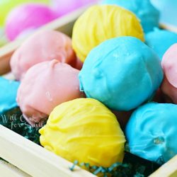 multi colored golden easter truffles in a wooden basket with shredded paper as grass
