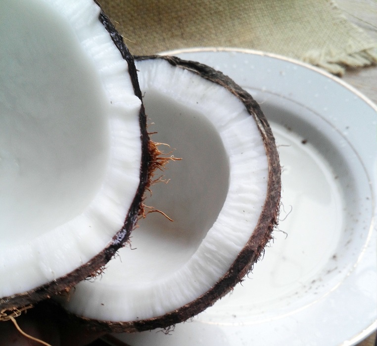 coconut cracked in half on a white plate 