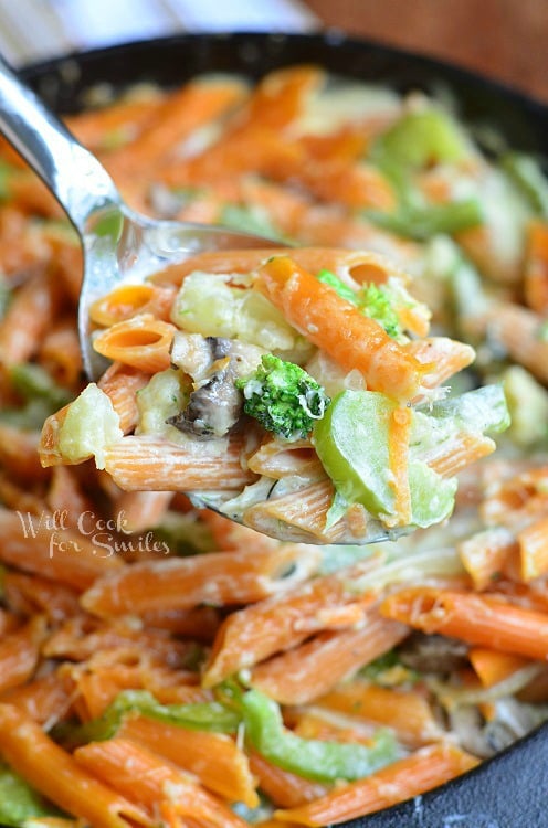 Pasta Primavera in a cast iron skillet with a metal spoon lifting some out 