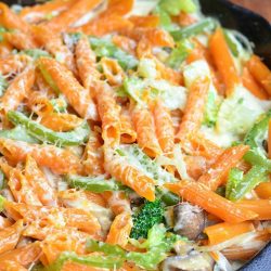 baked pasta primavera in a skillet on a brown colored cloth on wood table