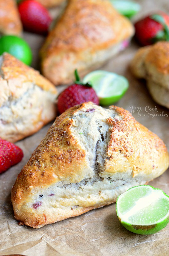 Strawberry Key Lime Scones on parchment paper with limes cut in half and strawberries 