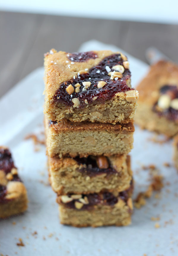 salted peanut butter and jelly blondies stacked up on a napkin 