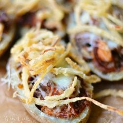 Potato skins on wax paper on wood table with onion tangler toppings