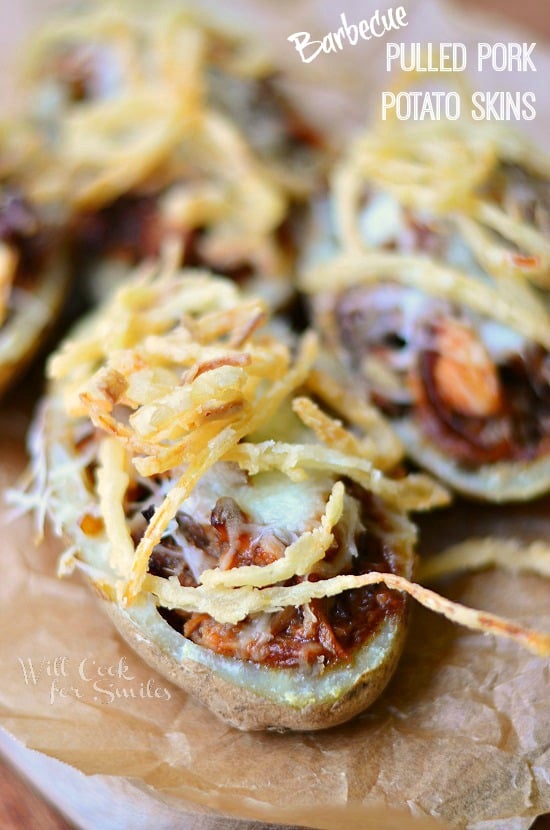 Potato skins on wax paper on wood table with onion tangler toppings